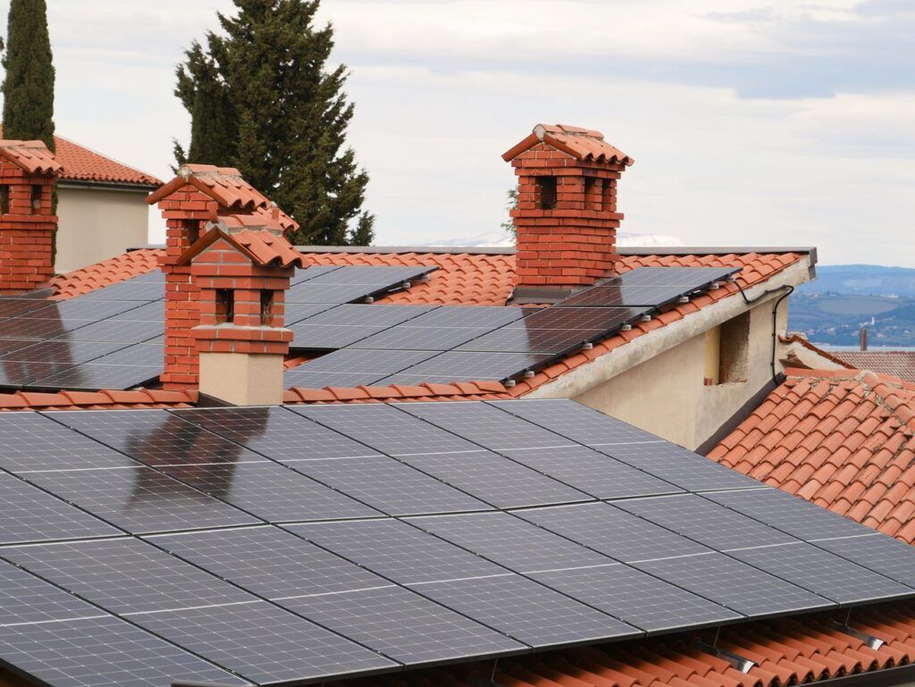 Importanța structurii de prindere și riscurile ascunse ale unui montaj de slabă calitate
Când se analizează ofertele instalatorilor fotovoltaici, aproape toată atenția se îndreaptă către marca panourilor și a invertorului. Cu toate acestea, elementul care dictează siguranța casei tale și integritatea fizică a întregului sistem este structura de susținere. Un kit de prindere ieftin sau un montaj realizat de personal necalificat transformă o investiție sigură într-un pericol real, care te poate costa scump pe termen lung.
Componentele unei structuri profesionale și materialele recomandate
Un sistem fotovoltaic adaugă o greutate constantă pe acoperiș, dar, mai ales, se comportă ca o velă uriașă în fața vântului puternic. Din acest motiv, fundația sistemului trebuie să fie impecabilă din punct de vedere mecanic.
Aluminiul anodizat și oțelul inoxidabil: Sunt singurele materiale care pot rezista decenii la rând în ploaie, zăpadă și variații extreme de temperatură fără să ruginească și fără să își piardă rezistența structurală.
Prinderile specifice tipului de învelitoare: O structură pentru țiglă ceramică folosește cârlige speciale care ocolesc țigla fără să pună greutate pe ea, în timp ce pe tabla fălțuită se folosesc cleme care strâng muchiile, fără a perfora deloc acoperișul.
Spațierea corectă pentru ventilație: Panourile trebuie montate la o distanță optimă față de învelitoare pentru a permite circulația aerului dedesubt. Dacă sunt montate prea aproape de tablă, panourile nu se mai răcesc eficient pe timpul verii, ceea ce le scade drastic producția din cauza supraîncălzirii.
Pericolele ascunse ale unui montaj executat greșit
Economia la manoperă sau alegerea unei oferte suspect de ieftine se plătește adesea cu reparații capitale la nivelul casei. Iată cele mai mari riscuri la care te expui dacă ignori calitatea prinderilor:
Infiltrațiile de apă: Dacă echipa perforează tabla necorespunzător și nu folosește garnituri EPDM de etanșare de înaltă calitate, apa se va infiltra treptat de fiecare dată când plouă, provocând putrezirea șarpantei de lemn a casei și degradarea izolației din pod.
Microfisurile din celulele solare: O șină de aluminiu prea subțire, care flambează sub greutatea zăpezii sau la rafale de vânt, va transmite tensiunea mecanică direct în sticla panourilor. Acest fenomen provoacă microfisuri (invizibile cu ochiul liber) în celulele de siliciu, ducând la pierderea definitivă a puterii și chiar la risc de incendiu prin formarea unui arc electric.
Anularea garanțiilor: Producătorii de panouri pot anula garanția echipamentelor dacă se constată, în urma unei expertize, că acestea au fost montate neconform, pe o structură flexibilă sau folosind puncte de prindere incorecte care nu respectă manualul de instalare.
Alegerea unei echipe de instalatori cu experiență atestată și utilizarea unor sisteme de prindere certificate reprezintă garanția că acoperișul tău va rămâne intact, iar sistemul fotovoltaic va funcționa la parametri optimi zeci de ani de acum înainte.